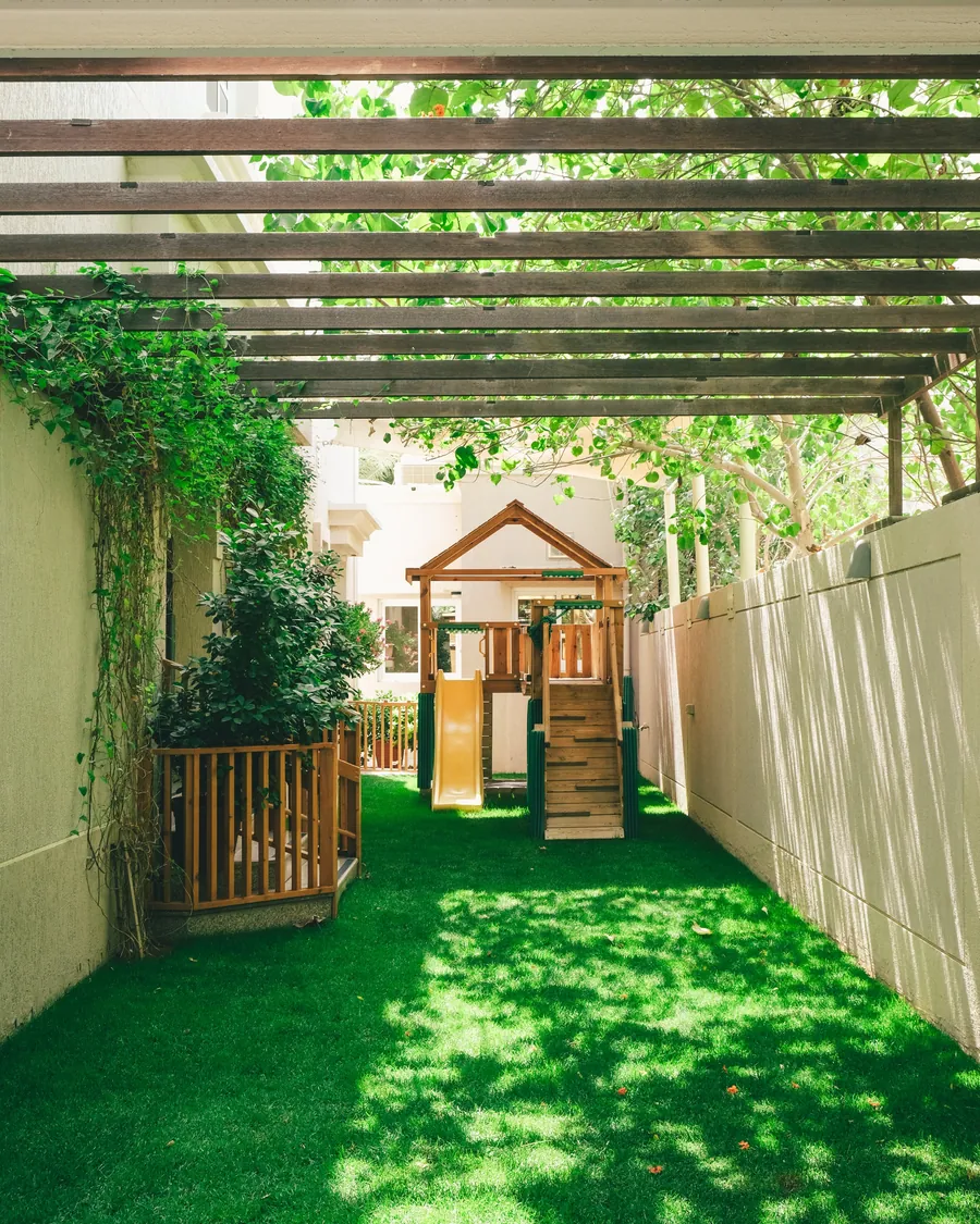 The AlMayameen garden with a wooden playhouse and green lawn
